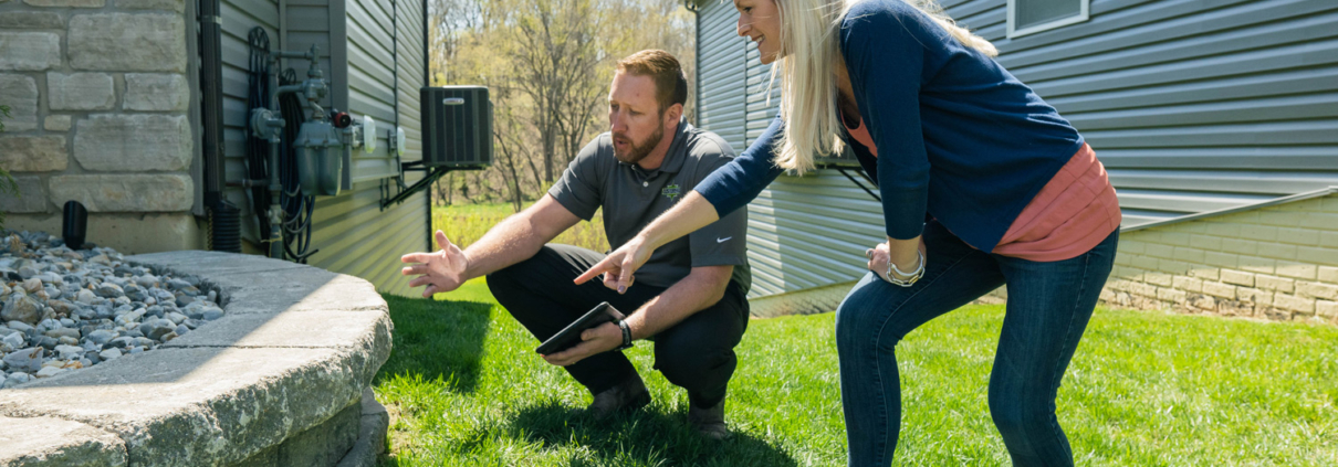 Amco Ranger pest control specialist conducting a detailed inspection with a homeowner, discussing potential rodent entry points around the house.