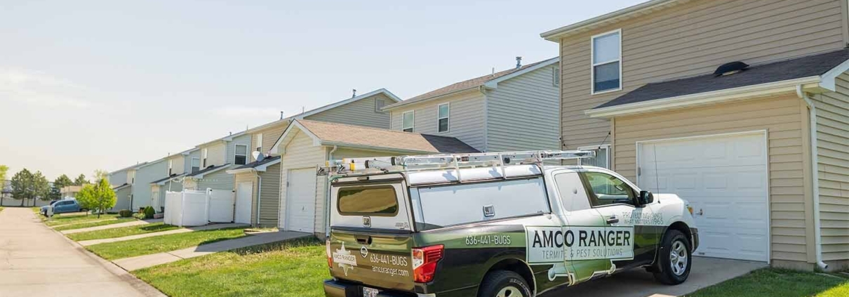 Amco Ranger pest control service truck parked in a residential driveway on a sunny day.