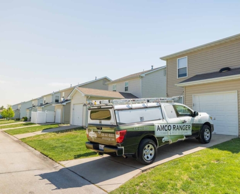 Amco Ranger pest control service truck parked in a residential driveway on a sunny day.