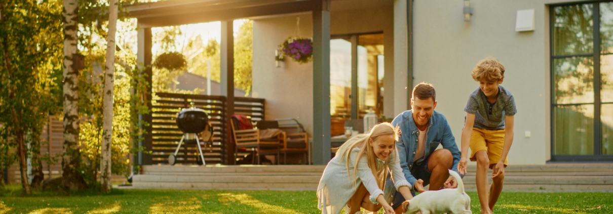 Happy family playing with their dog in a backyard treated with pet safe bug spray for a healthy, pest-free home.