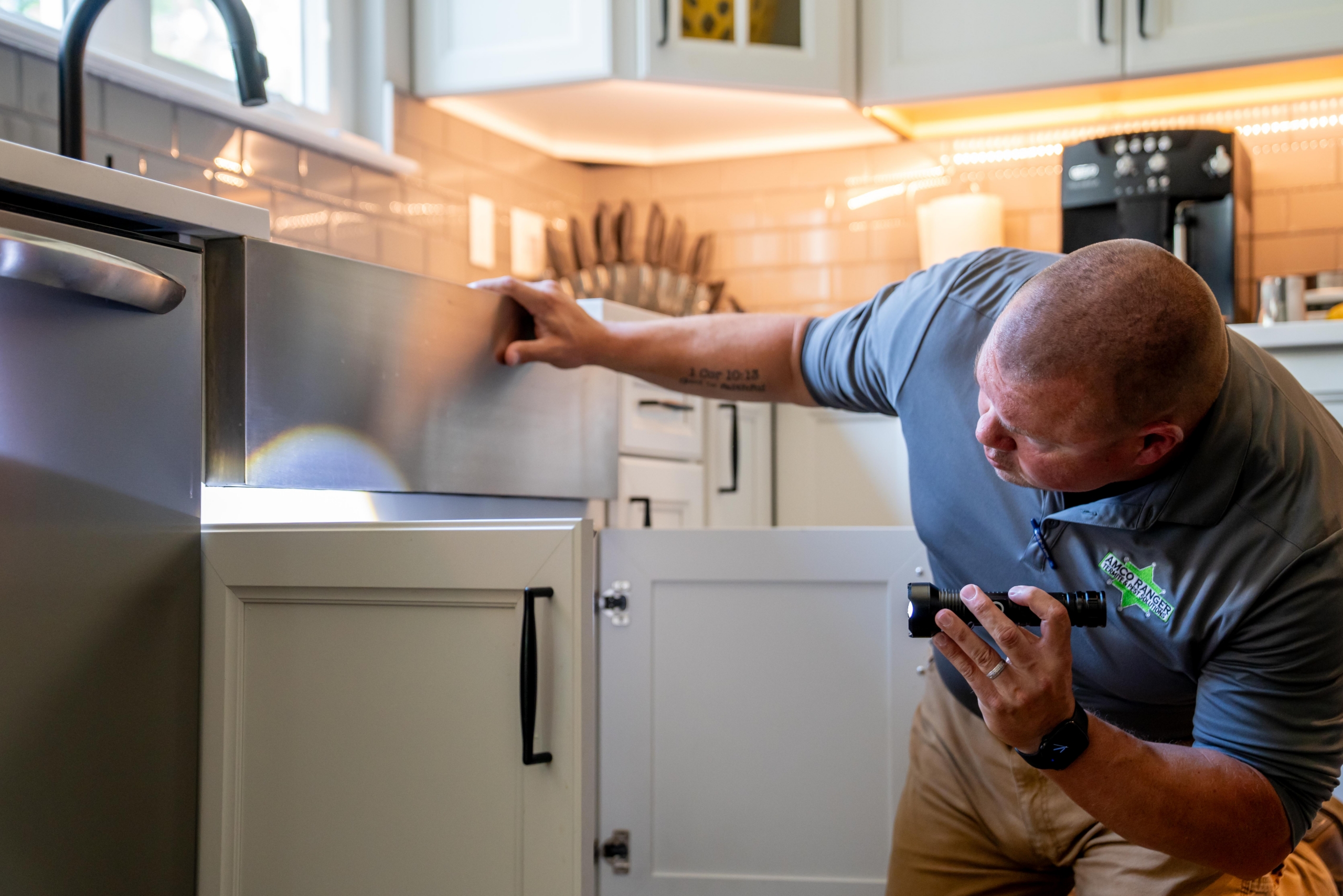 Amco Ranger pest control technician inspecting a home's kitchen cabinetry for signs of termite activity