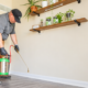 AMCO Ranger technician performing flea pest control indoors, using a hand sprayer to treat a baseboard